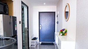 A modern hallway with a dark blue door, a white console table with a mirror, and a small shelf with shoes. - Lux Suites Riara One Residency Kilimani (Nairobi)
