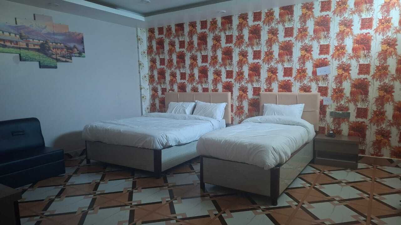 Una habitación con dos camas, un sofá y un papel tapiz estampado.