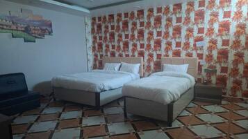 Una habitación con dos camas, un sofá y un papel tapiz estampado.