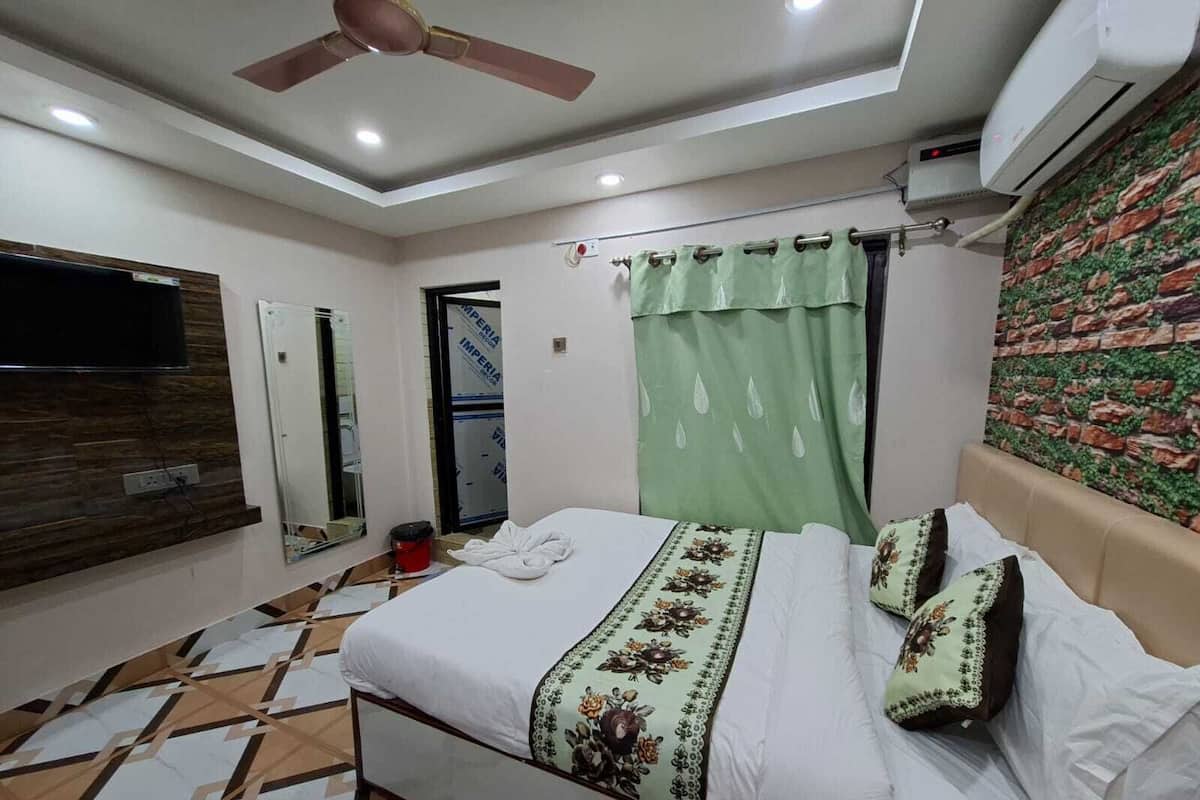 A bedroom with a bed, a ceiling fan, an air conditioning unit, a television, and a patterned floor.