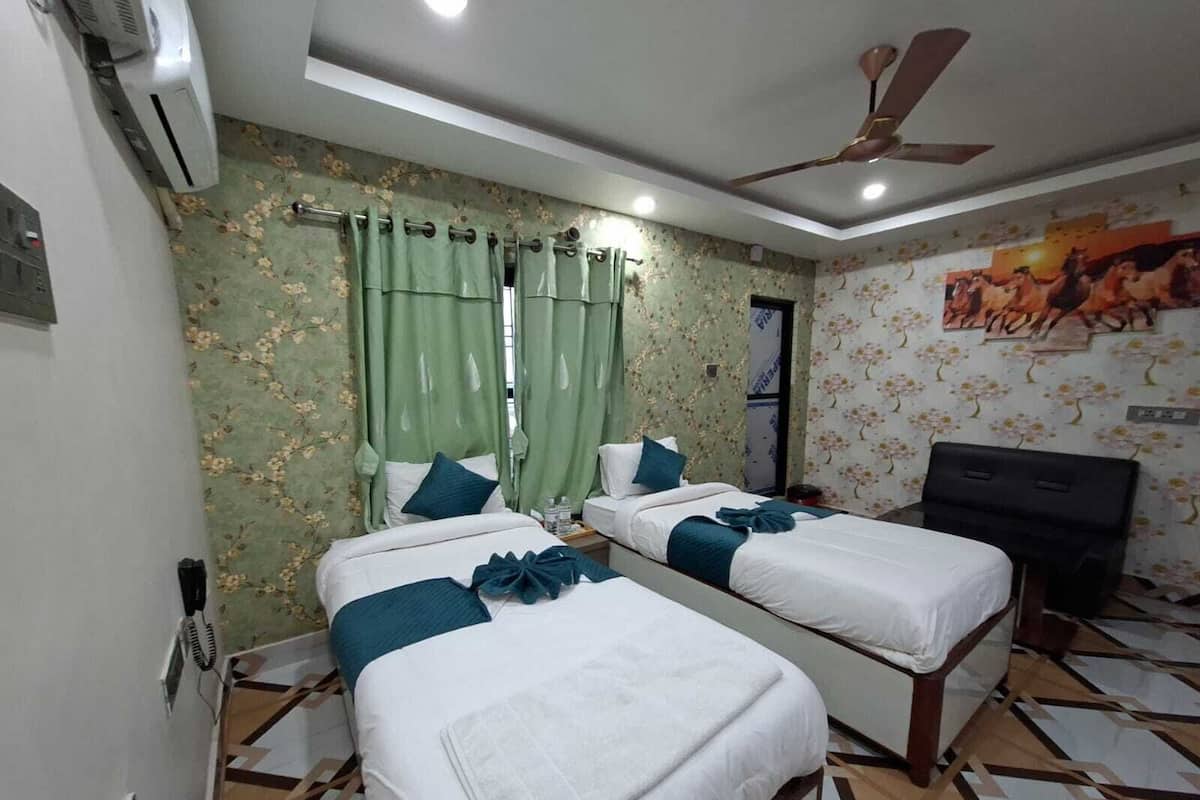 A hotel room with two beds, a ceiling fan, and a painting on the wall.
