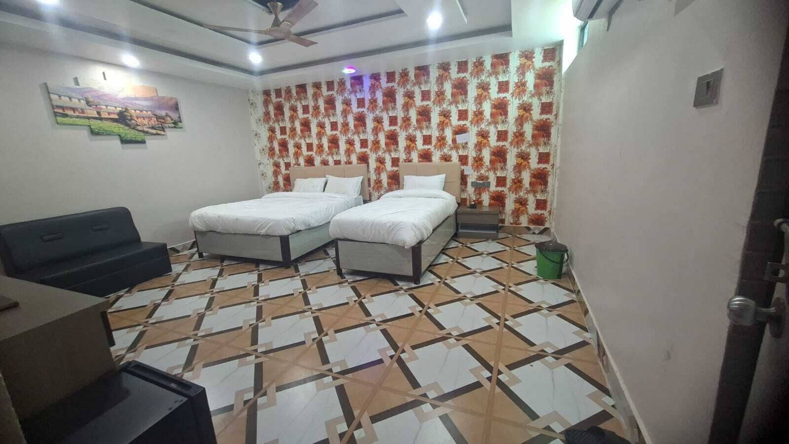 A room with two beds, a desk, a ceiling fan, and a patterned floor.