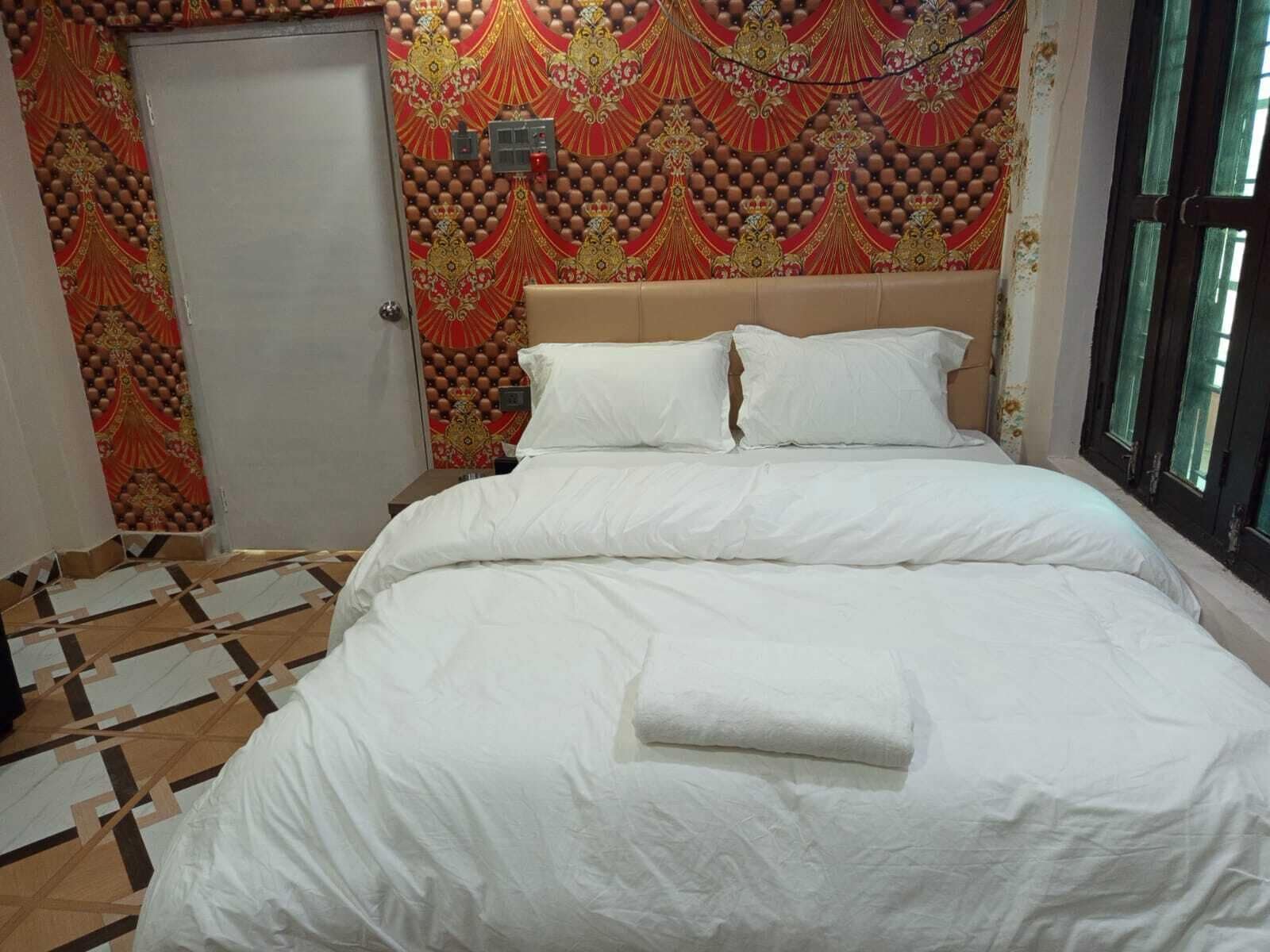 A hotel room with a bed, a patterned wall, and a door.