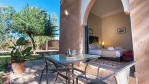 A hotel room with a bed, a table with a tray of breakfast items, a chair, and a view of the garden. - VILLA THAIFA (Marrakech)