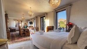 A hotel room with a large bed, a dining table, a TV, and a view of the outside. - VILLA THAIFA (Marrakech)