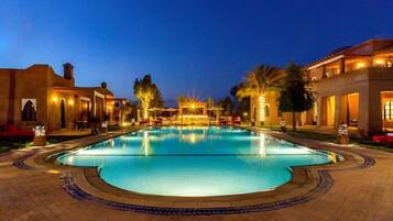 Una piscina al aire libre, sombrillas, sillones reclinables de piscina