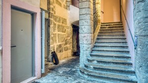 Eine enge Steintreppe führt zu einer oberen Etage, mit einer Tür und einer Tasche auf der linken Seite.