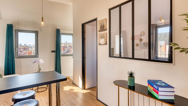 Ein modernes Wohnzimmer mit Essbereich, großen Fenstern und Blick auf die Stadt.