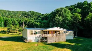 Einbungalow mit einer Veranda, einer überdachten Terrasse und einem kleinen Vorgarten.