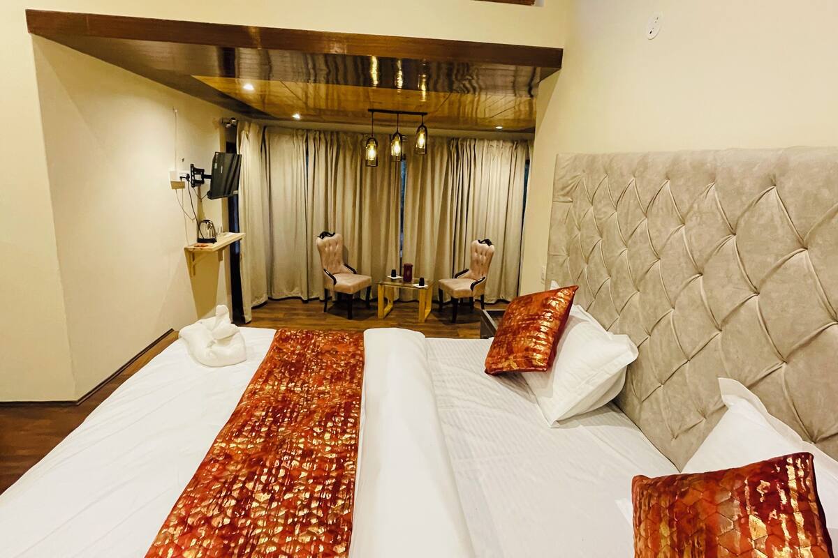 Una habitación de hotel con una cama grande, dos sillas, un escritorio y un televisor.