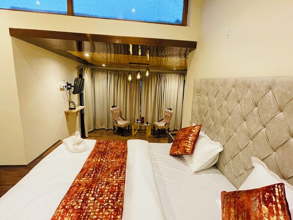 A hotel room with a large bed, two chairs, a desk, and a TV. - Thiksay Organic Resort and Retreat (Leh)