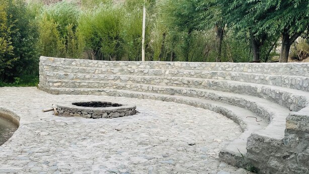A stone amphitheater with tiered seating, surrounded by greenery and mountains. - Thiksay Organic Resort and Retreat (Leh)
