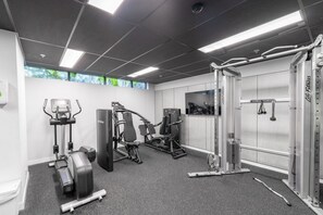 A gym with various exercise equipment, a pull-up bar, and a wall-mounted television.