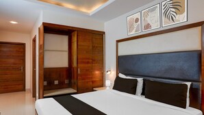 A hotel room with a large bed, wooden wardrobe, and artwork on the wall. - Super Townhouse Arcot Road (Chennai)