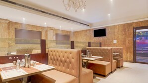 A modern restaurant with plush seating, a flat-screen TV, and a marble wall. - Super Townhouse Arcot Road (Chennai)