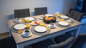 Ein Frühstückstisch mit Tellern, Besteck und einem Korb voller Croissants.