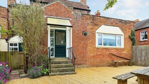 A brick house with a front door, a small window, and a wooden deck. - Brook House - UK43013 (Berkeley)