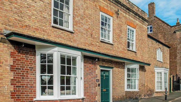 A brick building with multiple windows and doors, including a green door. - Brook House - UK43013 (Berkeley)