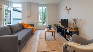 Una sala de estar moderna con un sofá gris, una mesita de centro y un televisor sobre un mueble.