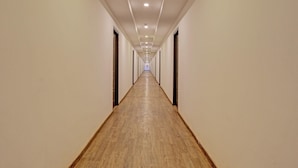 Un long couloir étroit, doté d’un plancher en bois et de murs blancs, qui mène à une porte au bout.