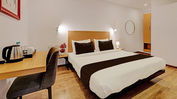 Une chambre d’hôtel comprenant un lit, une table de chevet, une chaise et un petit bureau avec une bouilloire et des tasses.