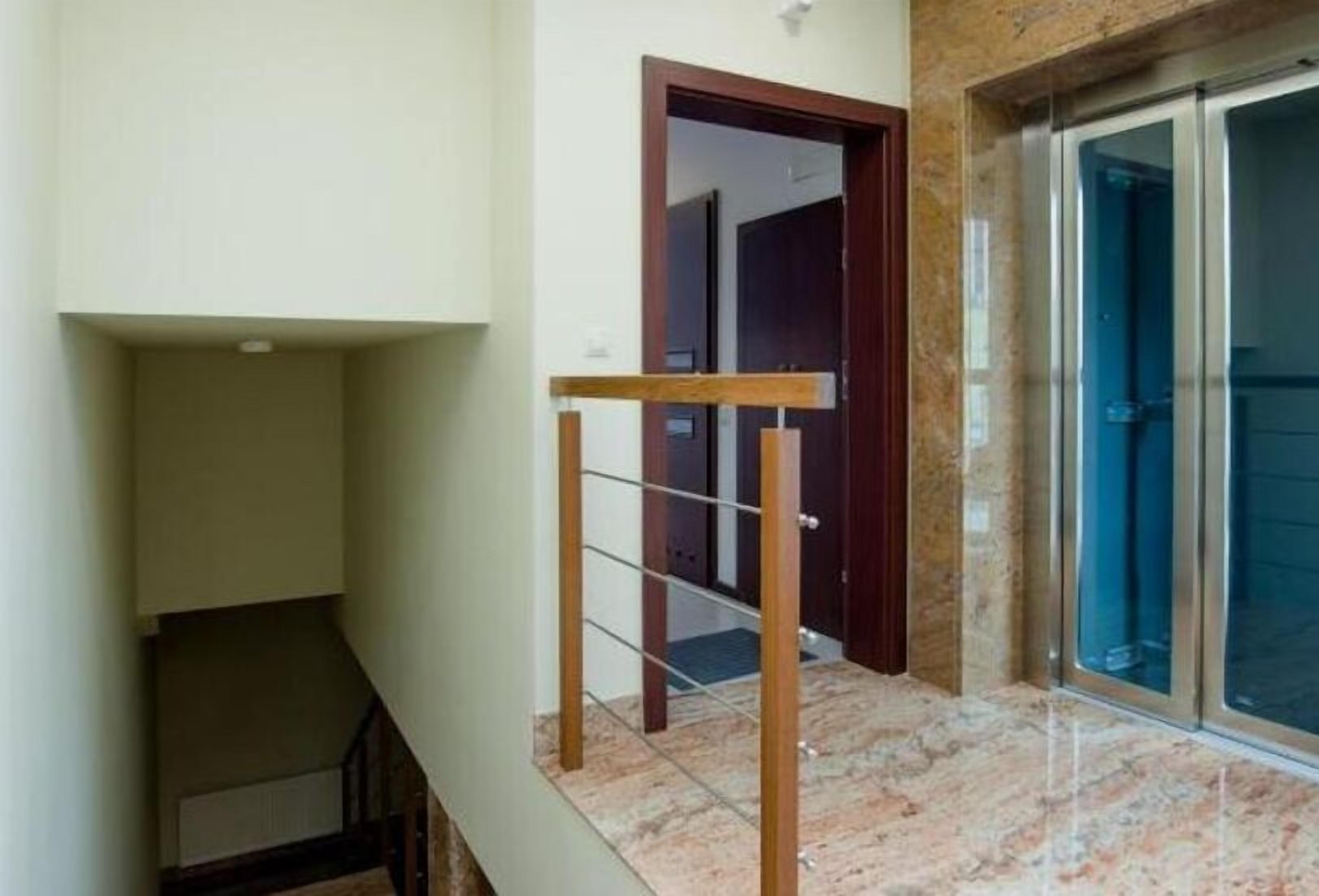 A staircase with a wooden handrail leading to a dark door.