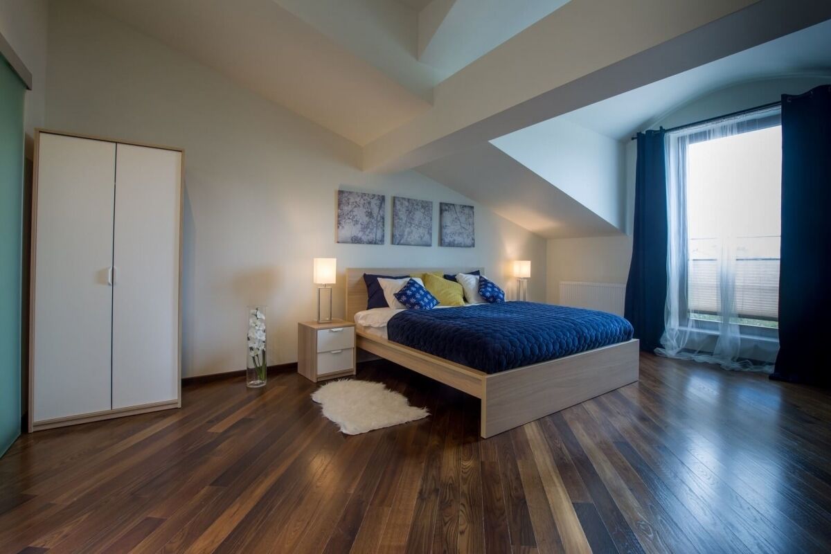 Een slaapkamer met een houten bed, nachtkastjes, een kledingkast en een dakraam.