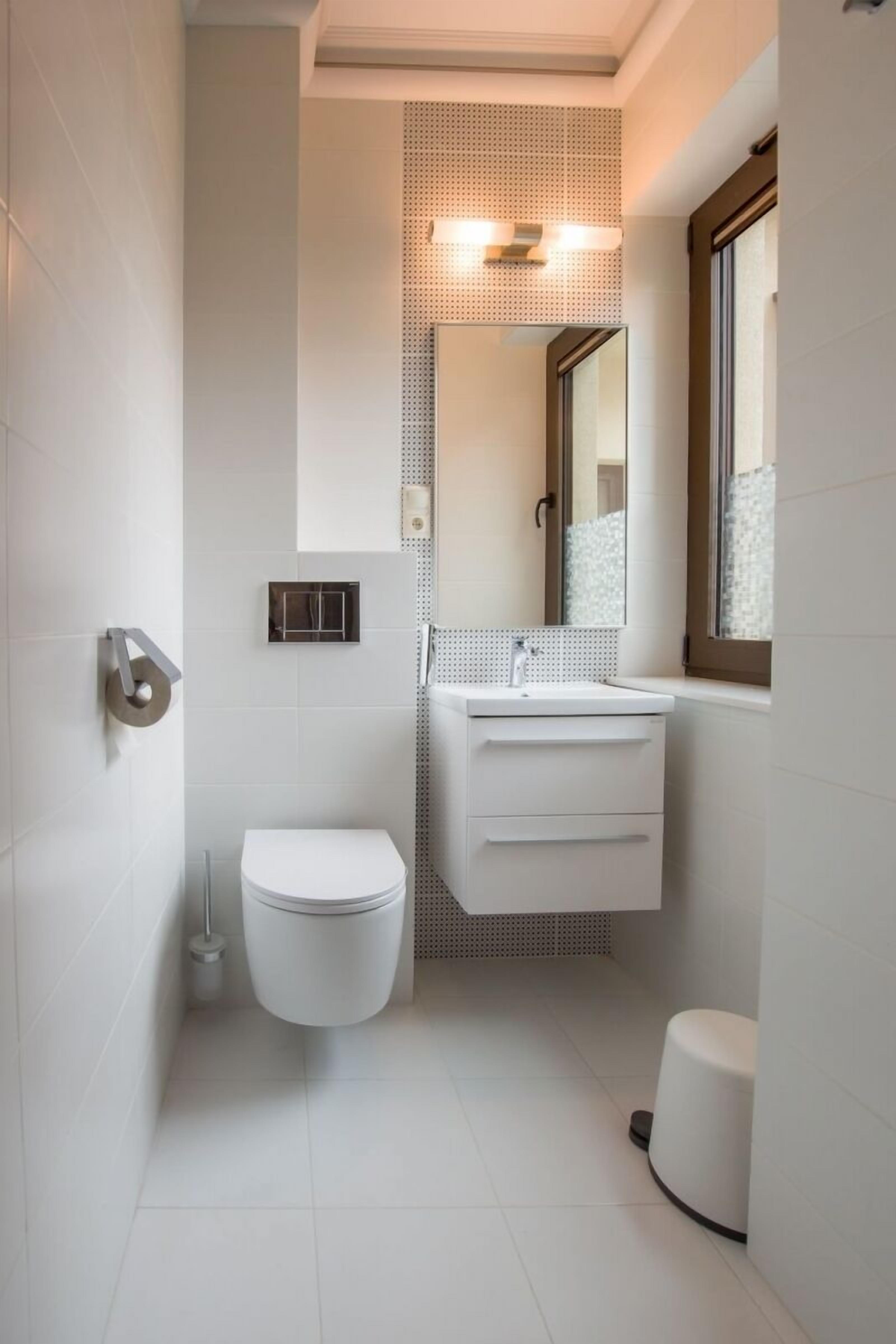 A modern bathroom with a toilet, sink, and mirror.