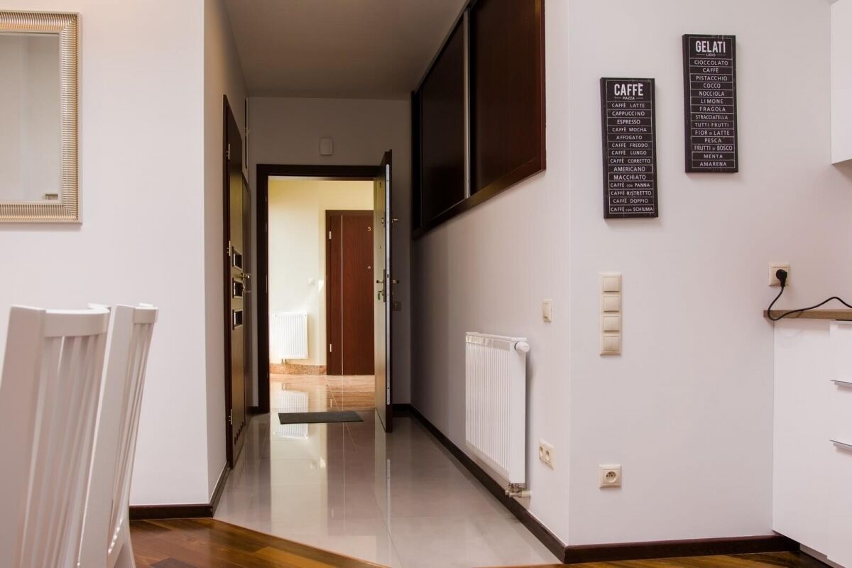 A hallway with a wooden floor, a white radiator, and a wall-mounted sign listing cafe beverages.