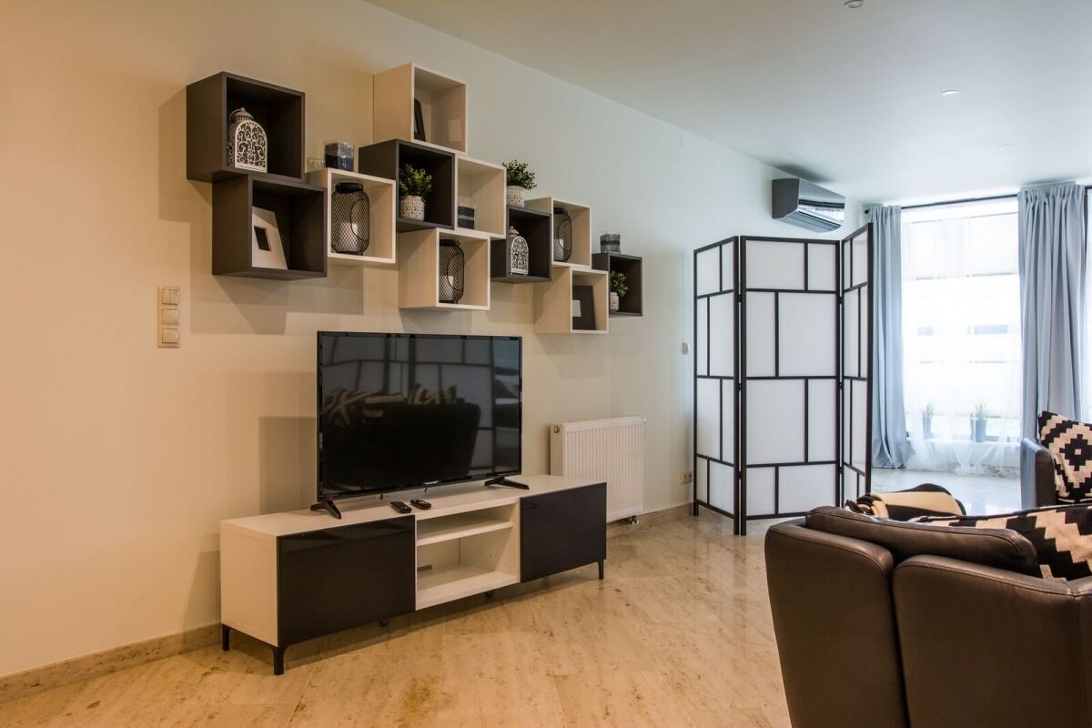 Una sala de estar moderna con un televisor de pantalla plana, un sofá y un mueble de almacenamiento decorativo.