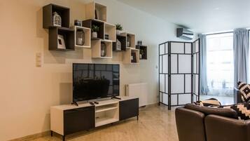 Una sala de estar moderna con un televisor de pantalla plana, un sofá y un mueble de almacenamiento decorativo.
