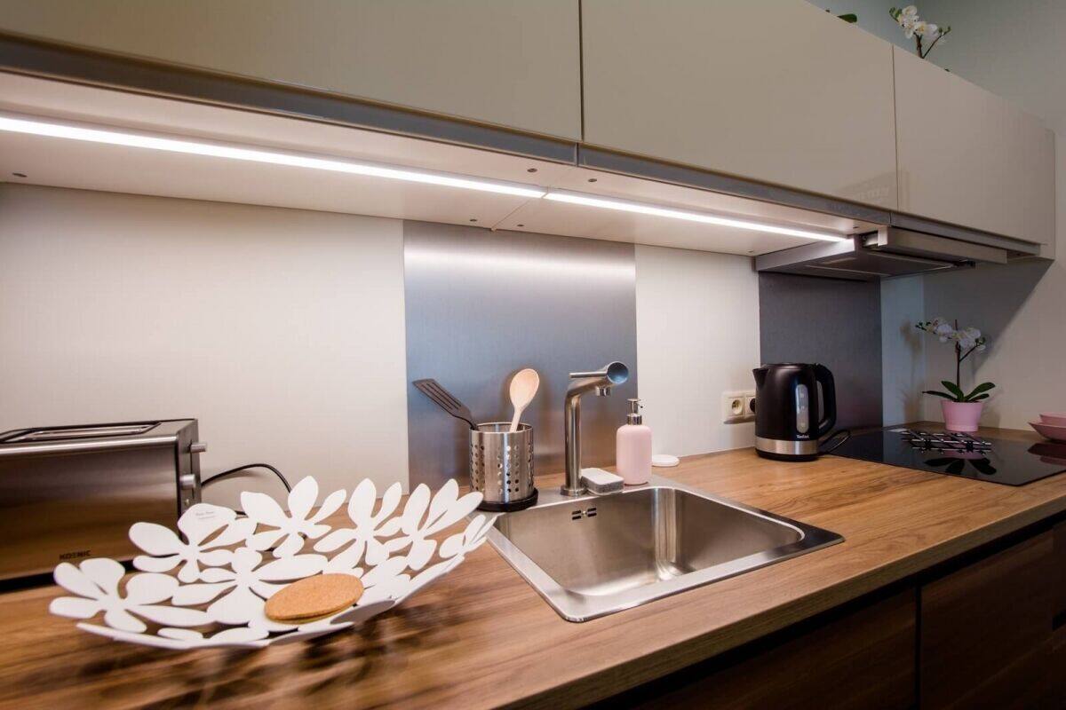 Una cocina moderna con un lavamanos de acero inoxidable, un tostador y un motivo decorativo de hoja blanca en la encimera.