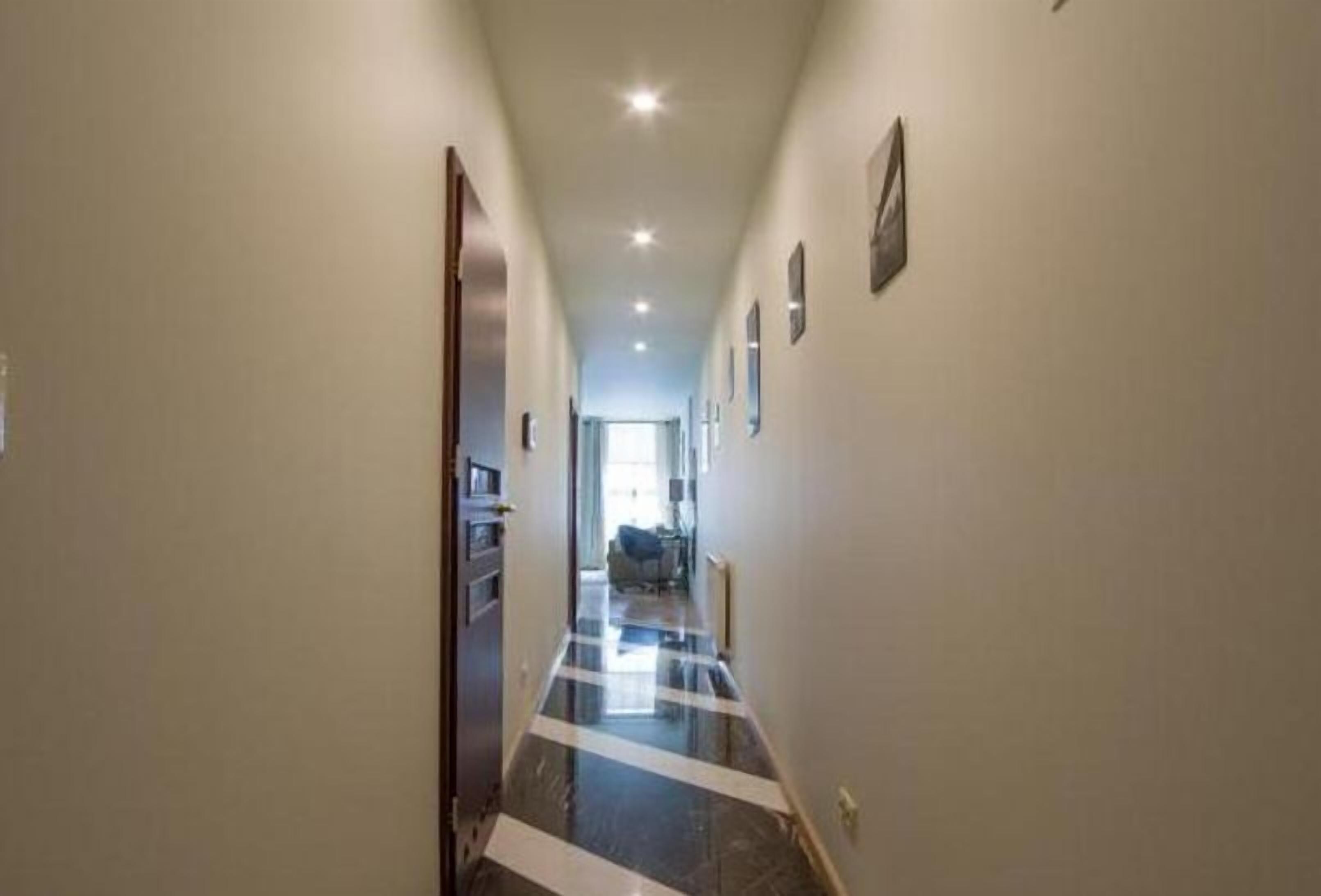 A narrow hallway with a polished floor and recessed lighting.