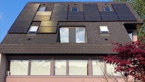Un bâtiment moderne doté d’un toit en pente, de nombreuses fenêtres et de panneaux solaires.