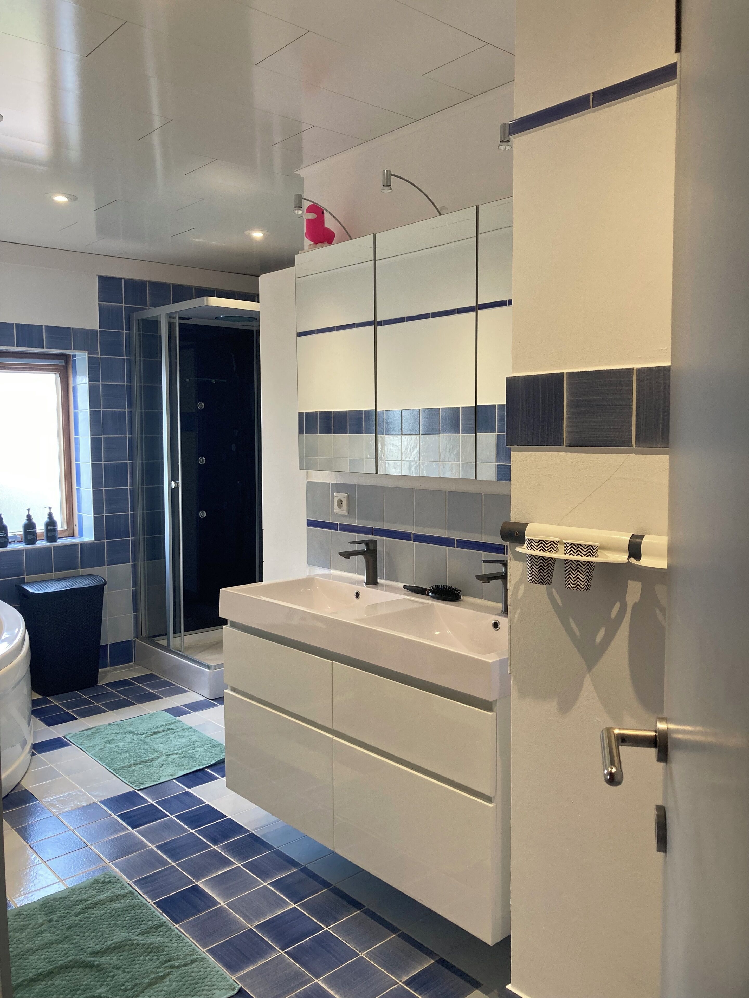 A modern bathroom with a large sink, a mirror, and a shower enclosure.