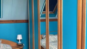 Une chambre à coucher avec un lit en bois, une table de chevet avec une lampe et une armoire à miroir.
