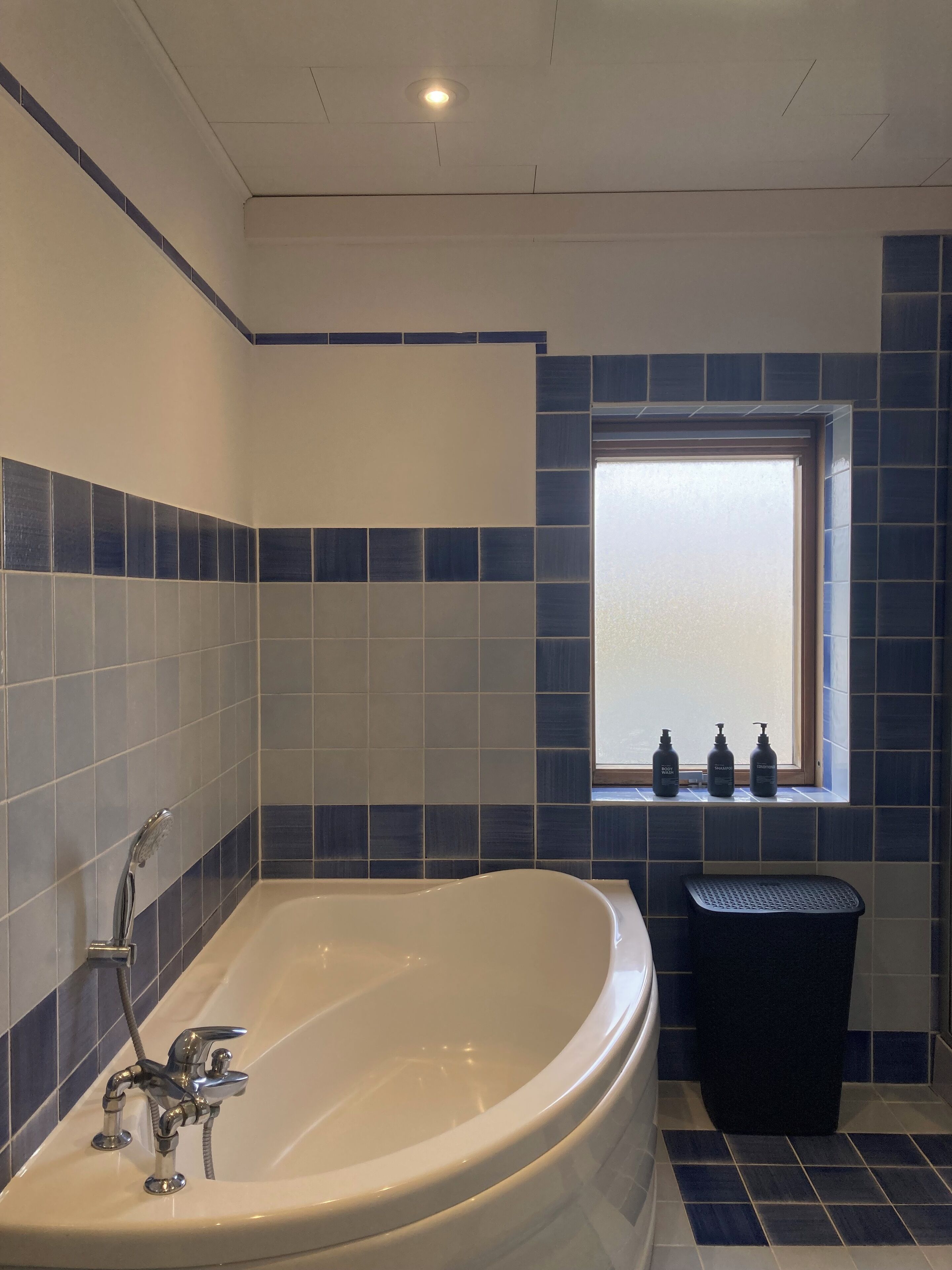 A bathroom with a freestanding bathtub, a window with a view, and a window sill with toiletries.