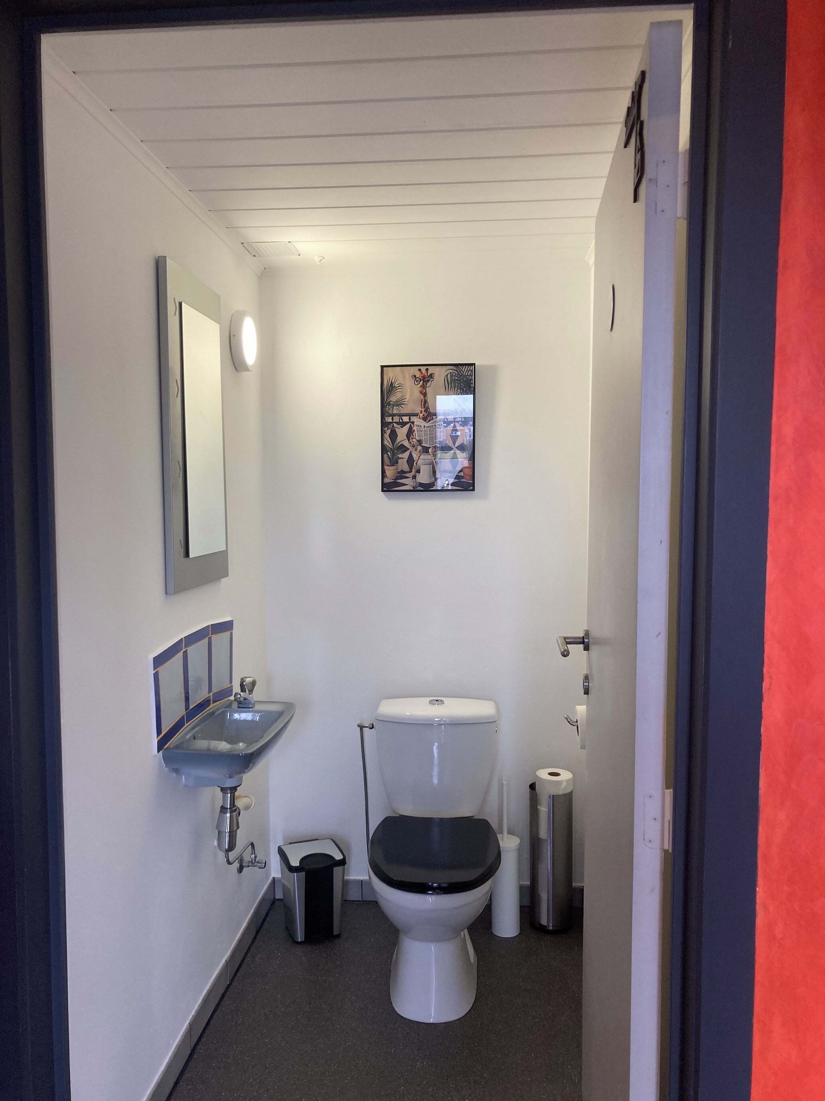 Casa de banho pequena e compacta, com sanita, lavatório e espelho.