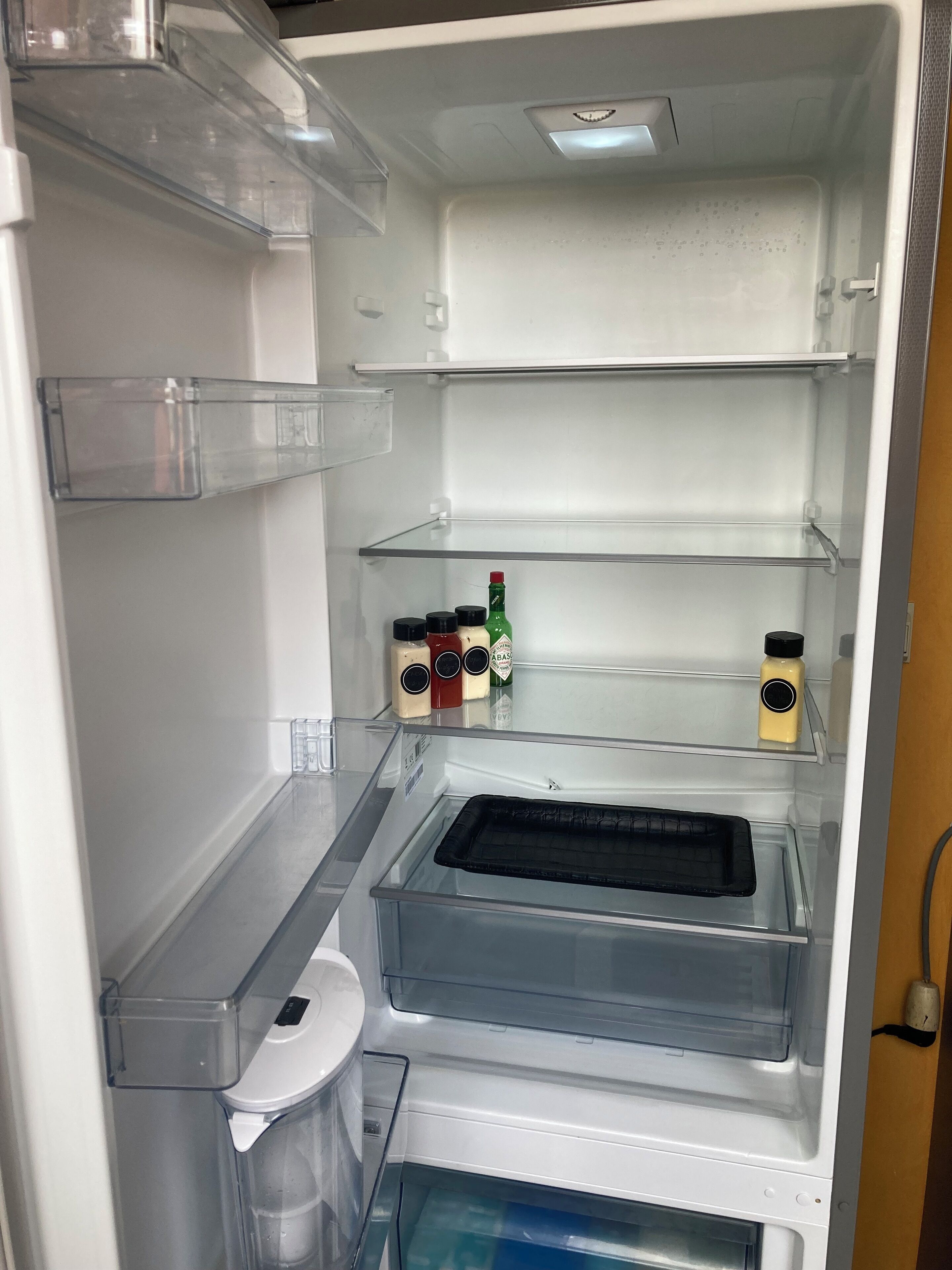 Ein leerer Kühlschrank mit mehreren Einlegeböden und einem separaten Gefrierfach.
