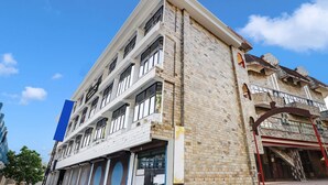 A multi-story hotel with a modern facade, large windows, and a prominent entrance. - Super Hotel O East Nada (Chavakkad)