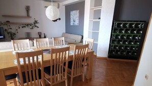 Un comedor con mesa y sillas de madera, una lámpara colgante y un salpicadero de azulejos verdes.