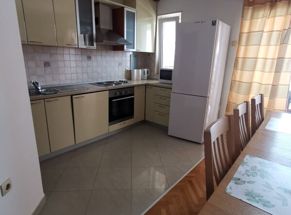 Una cocina con armarios color beige, estufa, horno y refrigerador.