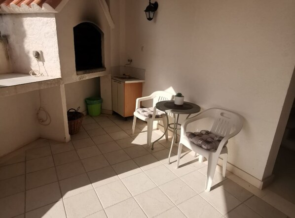 A small kitchen with a sink, a window, and a dining area with two chairs and a small table. - Apartment Gilletino (Dugi Rat)