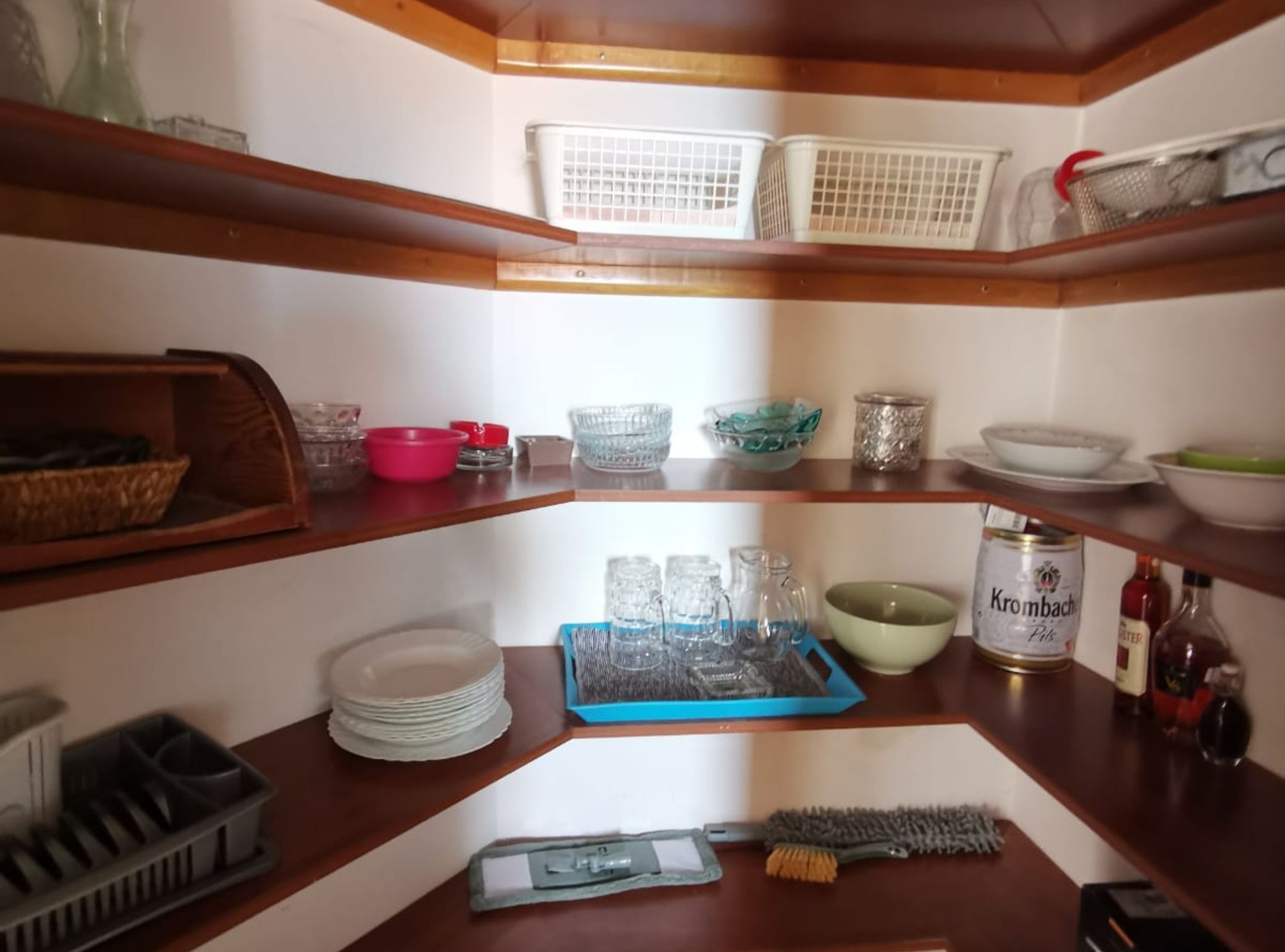 A kitchen with wooden shelves, a blue tray, and various kitchenware.