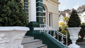 A building with the name "ANNA" on the facade, a staircase with white balustrades, and large white urns on the steps. - Annan Hotel (Llandudno)