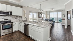 A modern kitchen with white cabinets, stainless steel appliances, and a large island.