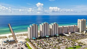 A coastal hotel with multiple high-rise buildings, a beach, and a pier.