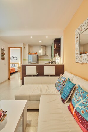 A modern living room with a sofa, a coffee table, and a kitchen in the background.