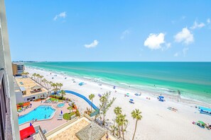 A beach resort with a swimming pool, palm trees, and a view of the ocean. - 🐬Stunning 2BR Beachfront Condo with Gulf Views & a Gorgeous Pool!– Ocean Sands Unit 903🐬 (Madeira Beach)