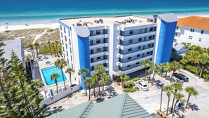A multi-story hotel with a pool, beach view, and parking area.